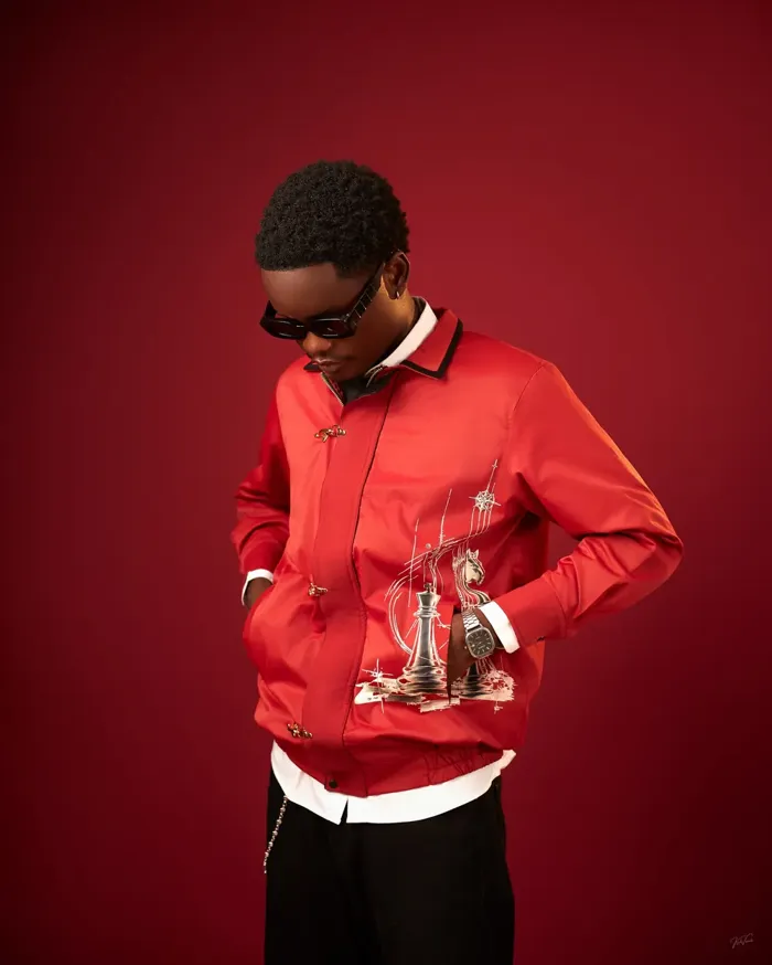 Model looking down in the red Board Jacket with a silver chess print and gold clasps