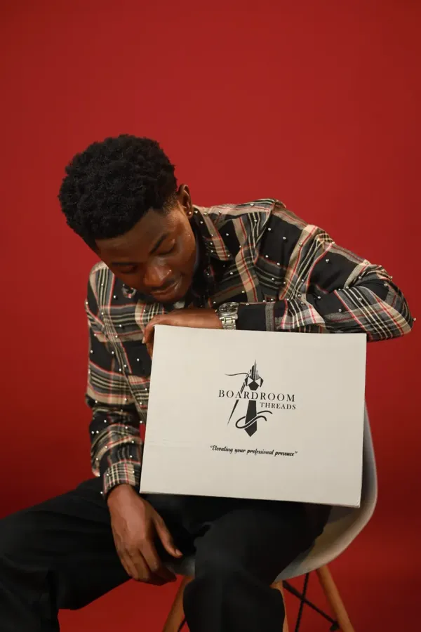 Model in the beaded plaid shirt holding the Boardroom Threads gift box