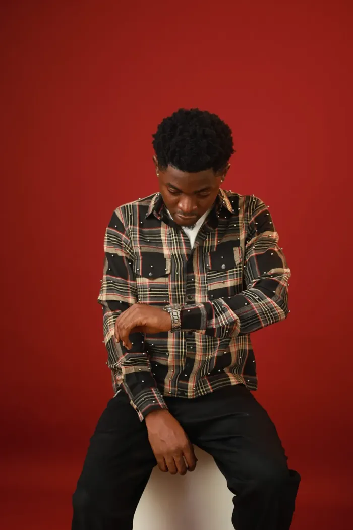 Model in the beaded plaid shirt looking down at his watch